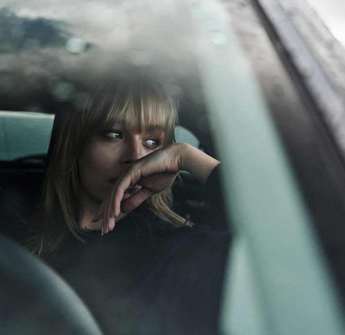 jeune femme à l'intérieur d'une DS 3 qui regarde vers l'extérieur de la vitre latérale