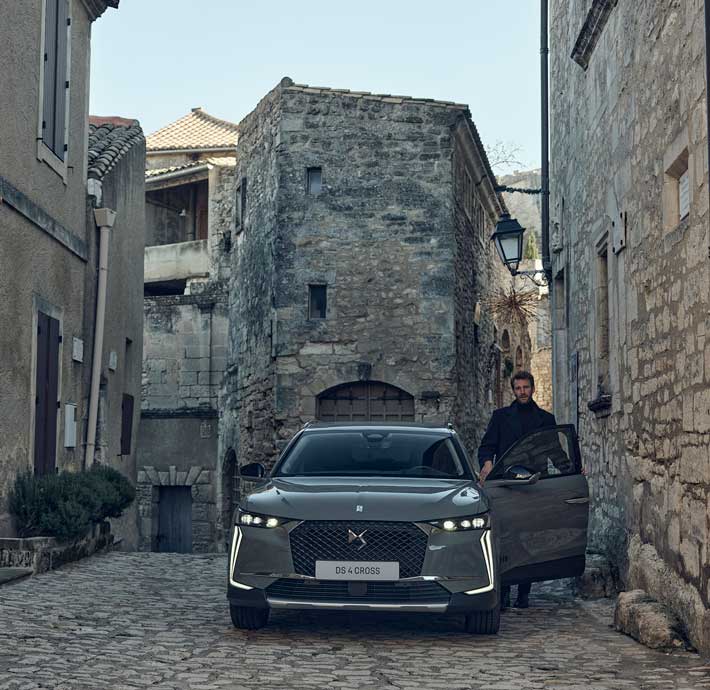 homme qui ouvre une porte de voiture DS 4 dans une rue d'un village