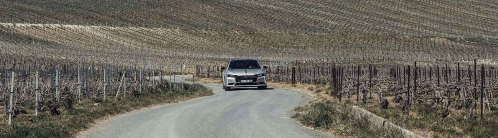 Berline qui roule sur une petite route au milieux des vignes